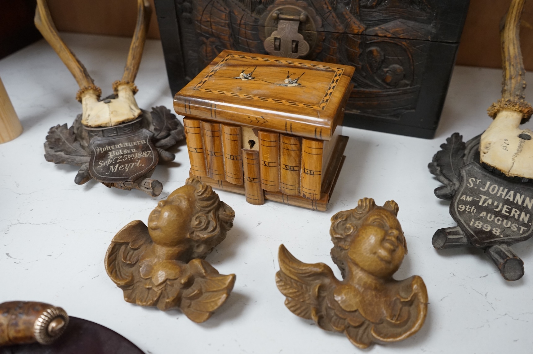 A Chinese carved wood box, two pairs of mounted deer horns, two carved wood cherub heads, an ashtray and an olivewood box, large box 29.5cm x 15cm high. (7)